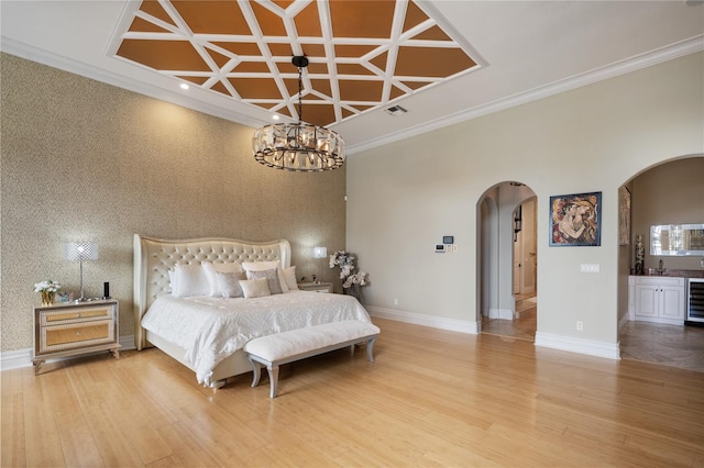 bedroom with wine cooler, ornamental molding, connected bathroom, and coffered ceiling