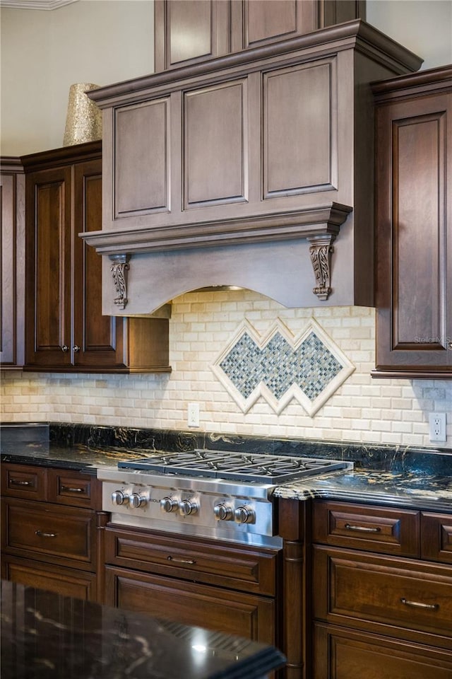 kitchen with tasteful backsplash, dark stone countertops, dark brown cabinets, and stainless steel gas cooktop