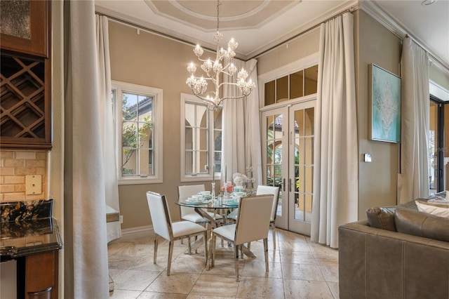 dining room featuring a tray ceiling, french doors, a chandelier, and ornamental molding