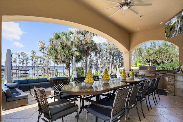 view of patio / terrace featuring ceiling fan, exterior kitchen, a grill, an outdoor hangout area, and a water view