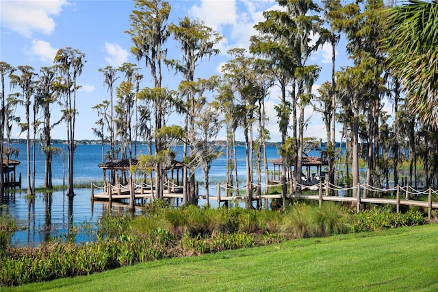 view of dock with a water view and a yard