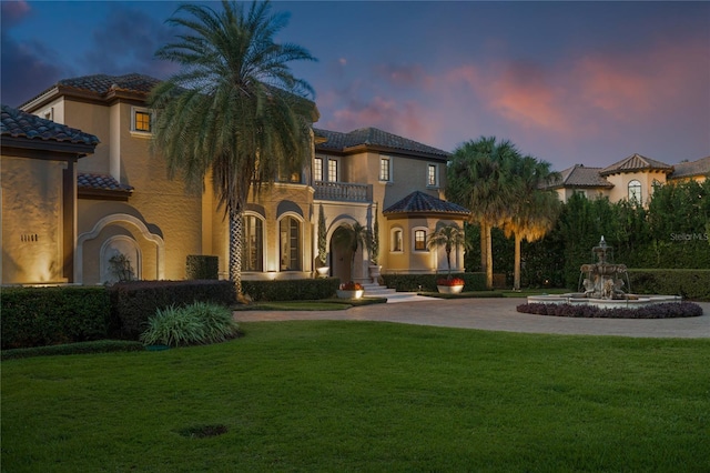 mediterranean / spanish-style house with a lawn and a balcony