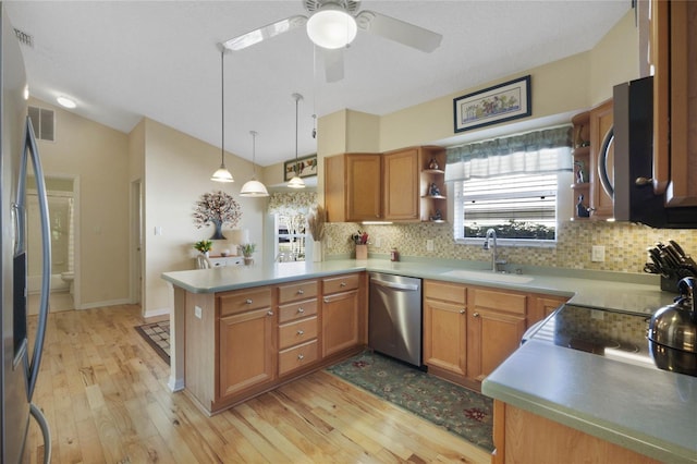 kitchen featuring sink, light wood-type flooring, decorative light fixtures, kitchen peninsula, and stainless steel appliances