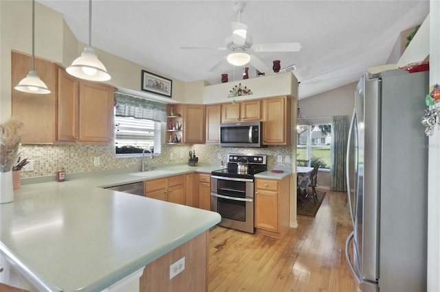 kitchen with kitchen peninsula, appliances with stainless steel finishes, sink, pendant lighting, and lofted ceiling