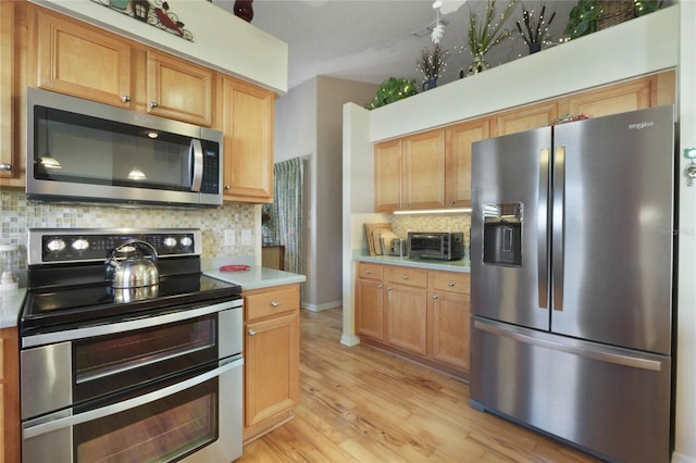 kitchen with stainless steel appliances, tasteful backsplash, and light hardwood / wood-style floors