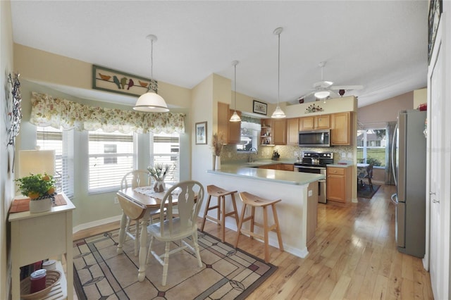 kitchen with sink, decorative backsplash, light wood-type flooring, decorative light fixtures, and stainless steel appliances