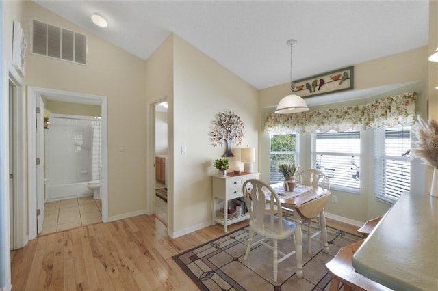 dining area featuring vaulted ceiling and light wood-type flooring