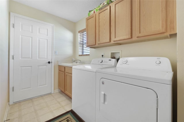 clothes washing area with washer and dryer, cabinets, and sink