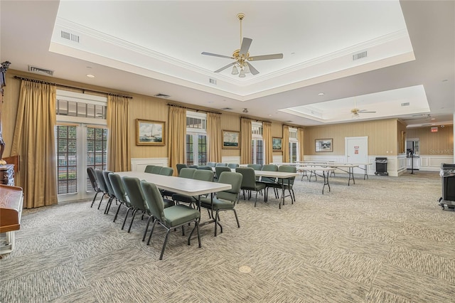 carpeted dining area featuring a raised ceiling, ceiling fan, and crown molding