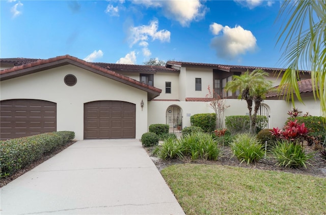 mediterranean / spanish-style house with a garage, driveway, and stucco siding