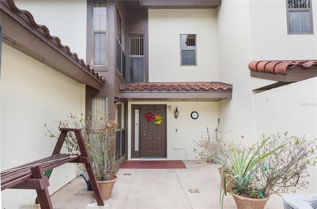 doorway to property featuring a tile roof and stucco siding