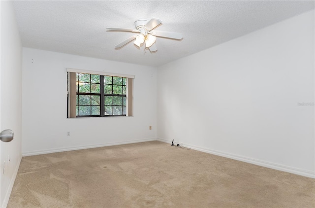 spare room featuring light carpet, ceiling fan, a textured ceiling, and baseboards