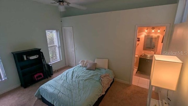 carpeted bedroom with ensuite bath and ceiling fan