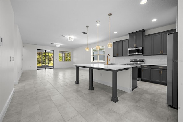 kitchen featuring sink, hanging light fixtures, backsplash, a center island with sink, and appliances with stainless steel finishes