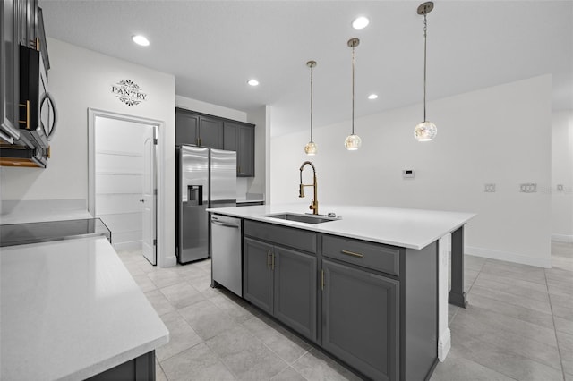 kitchen featuring appliances with stainless steel finishes, sink, pendant lighting, a center island with sink, and gray cabinets