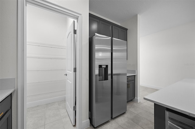 kitchen with stainless steel fridge with ice dispenser and a textured ceiling