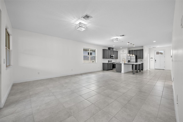 unfurnished living room with sink and light tile patterned flooring