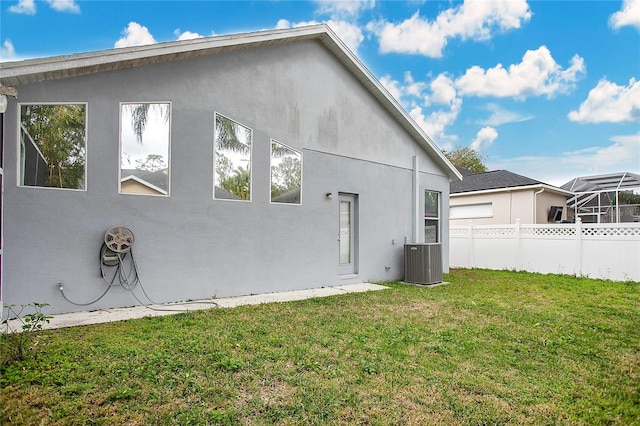 rear view of property featuring a lawn and central AC unit