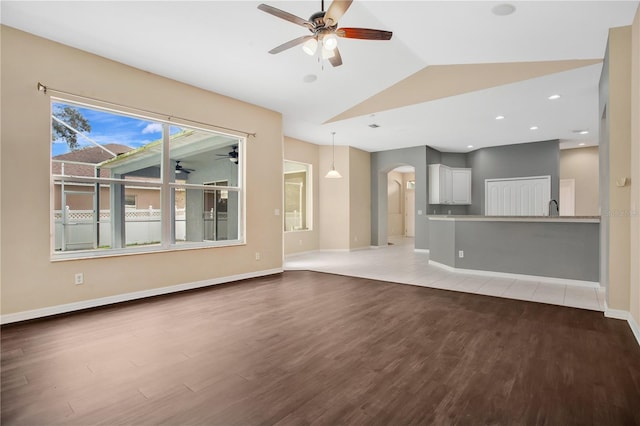 unfurnished living room featuring sink, vaulted ceiling, and hardwood / wood-style flooring