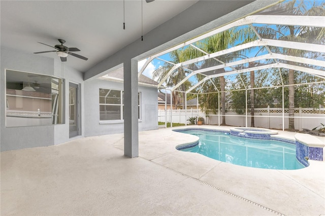 view of pool featuring glass enclosure, ceiling fan, a patio, and an in ground hot tub