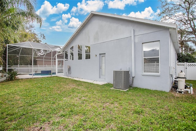 rear view of property with glass enclosure, cooling unit, and a yard