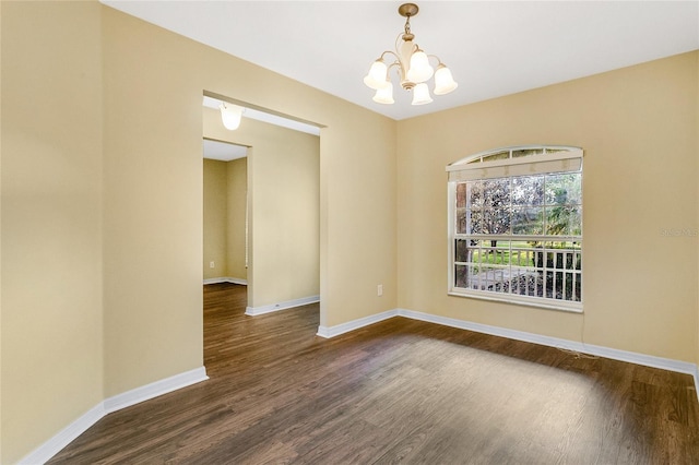 empty room featuring dark hardwood / wood-style flooring and a notable chandelier