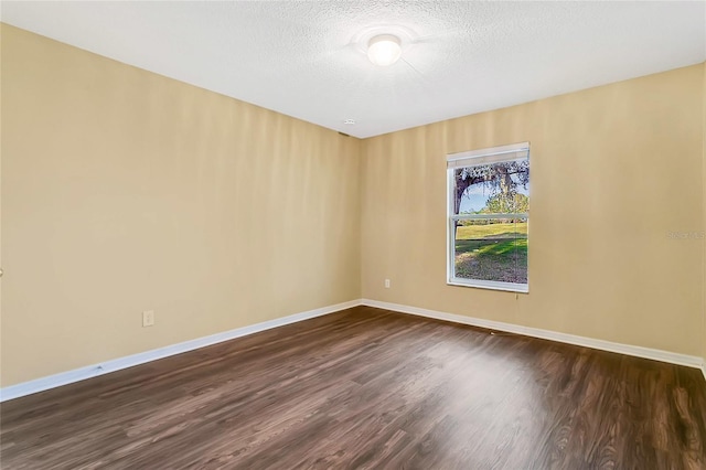 empty room with a textured ceiling and dark wood-type flooring