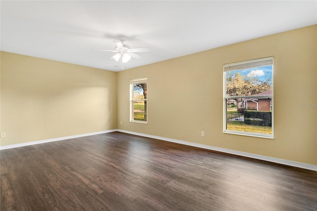 spare room featuring plenty of natural light, ceiling fan, and dark wood-type flooring