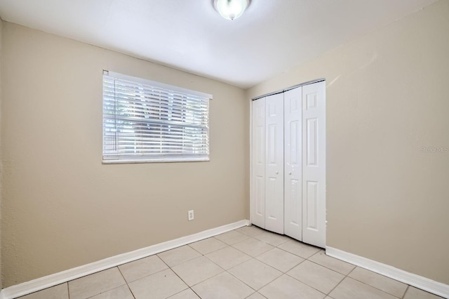 unfurnished bedroom with light tile patterned flooring and a closet