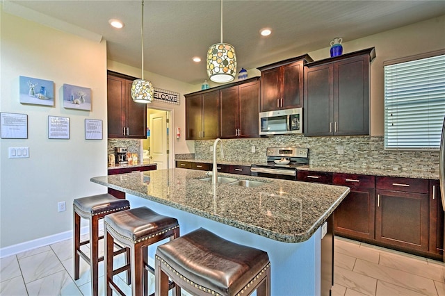 kitchen with sink, a center island with sink, light stone countertops, and appliances with stainless steel finishes