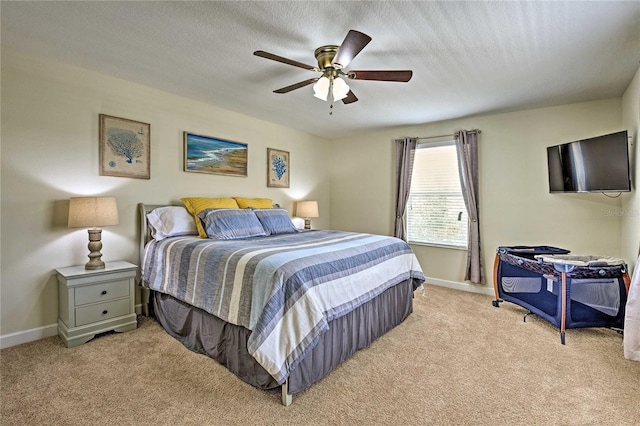 bedroom with ceiling fan, light carpet, and a textured ceiling