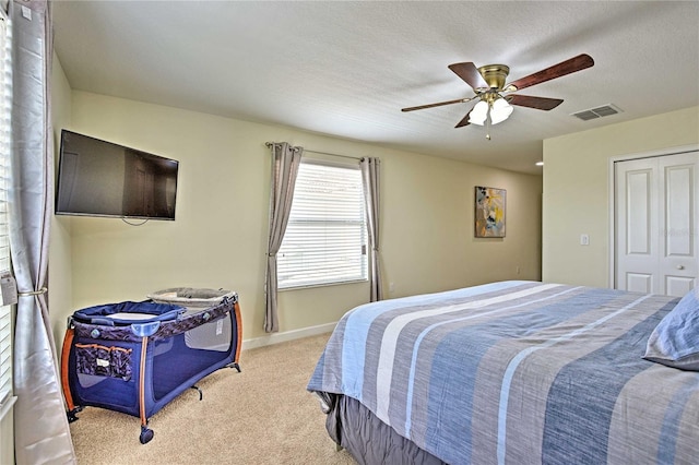 bedroom featuring a textured ceiling, a closet, ceiling fan, and light colored carpet