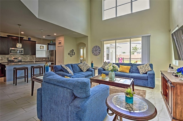 1636 Moon Valley Dr, Davenport, FL 33896 - living area featuring light marble finish flooring, healthy amount of natural light, arched walkways, a towering ceiling, and recessed lighting