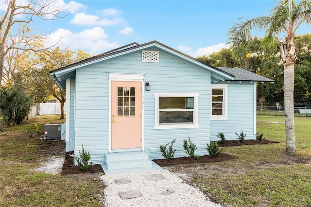 bungalow-style house featuring cooling unit and a front lawn