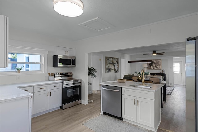 kitchen with white cabinets, sink, ceiling fan, appliances with stainless steel finishes, and light hardwood / wood-style floors