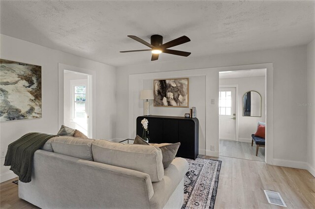 living room with plenty of natural light, ceiling fan, light hardwood / wood-style flooring, and a textured ceiling