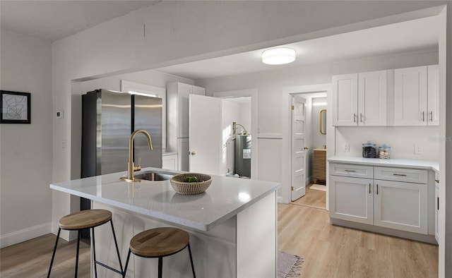 kitchen featuring white cabinets, a kitchen breakfast bar, sink, and an island with sink