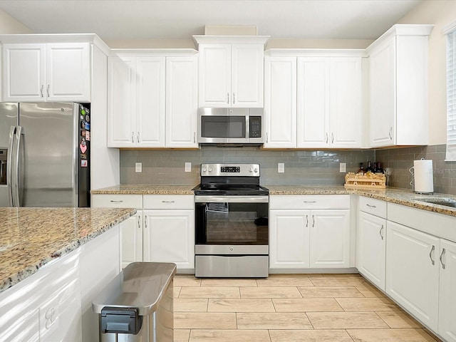 kitchen featuring decorative backsplash, white cabinetry, and stainless steel appliances