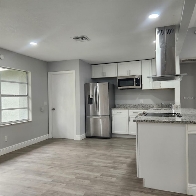 kitchen featuring white cabinets, light hardwood / wood-style flooring, light stone countertops, appliances with stainless steel finishes, and island exhaust hood