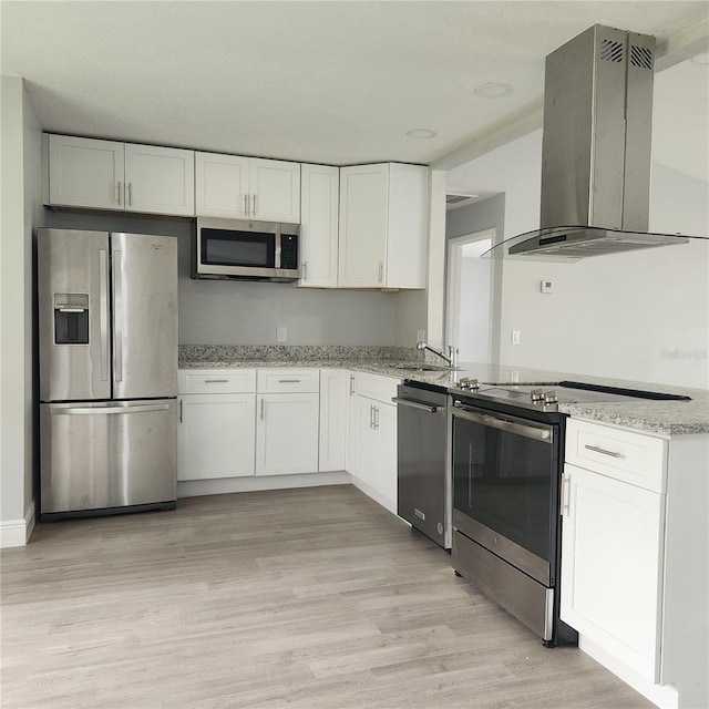 kitchen featuring light stone counters, light wood-style flooring, island range hood, white cabinets, and stainless steel appliances