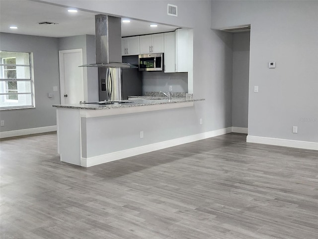 kitchen featuring visible vents, a peninsula, stainless steel appliances, and island range hood