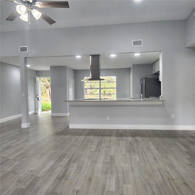 unfurnished living room featuring visible vents, baseboards, and light wood-style floors