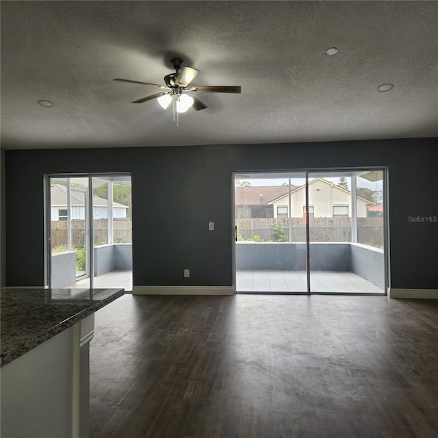 spare room with dark wood finished floors, plenty of natural light, and baseboards