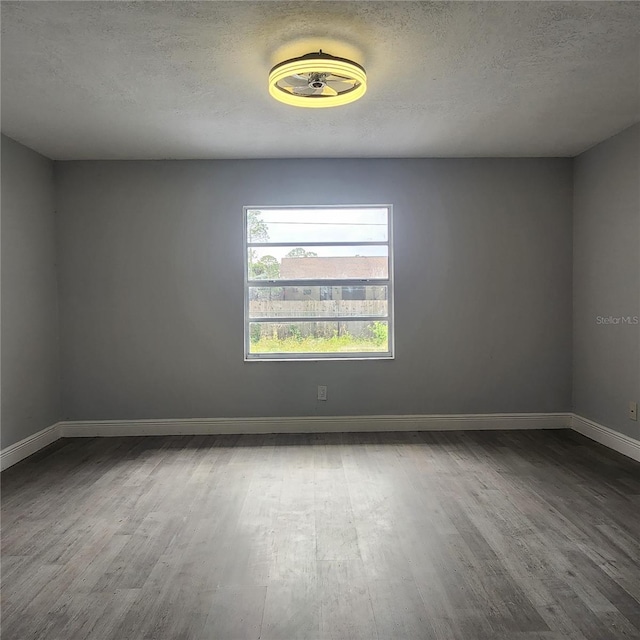 unfurnished room with wood finished floors, baseboards, and a textured ceiling