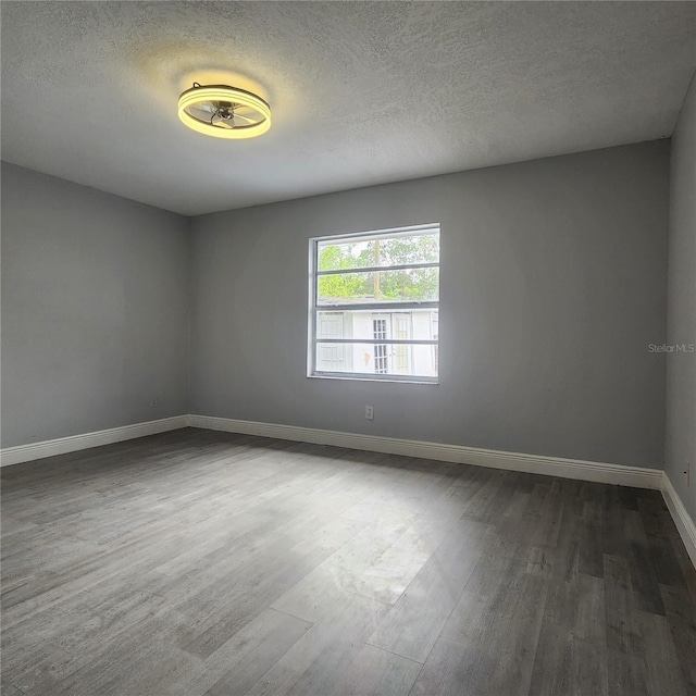 unfurnished room featuring dark wood-type flooring, baseboards, and a textured ceiling