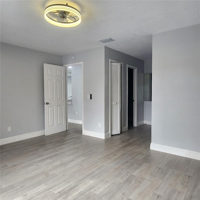 spare room with visible vents, a textured ceiling, baseboards, and wood finished floors