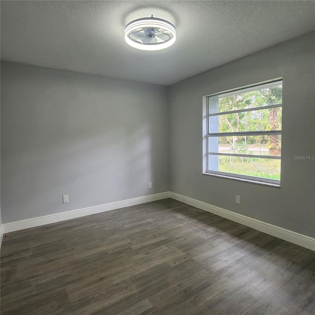 unfurnished room with baseboards, a textured ceiling, and dark wood-style flooring