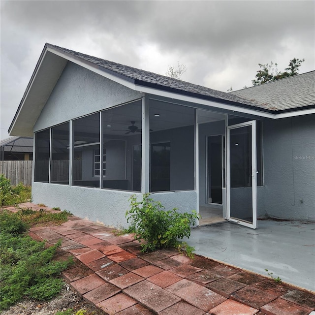 rear view of house featuring a patio area, stucco siding, roof with shingles, and fence