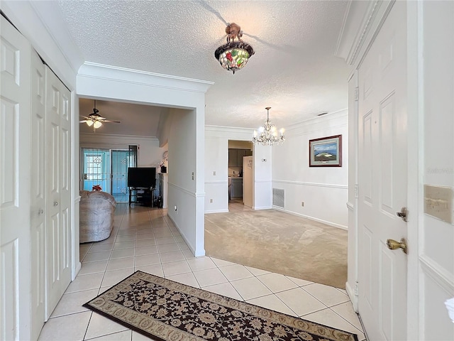 hallway with crown molding, light colored carpet, a textured ceiling, and a notable chandelier