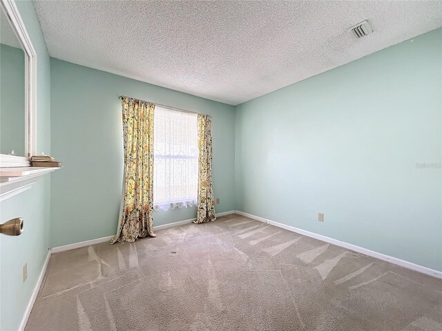 empty room featuring a textured ceiling and light colored carpet